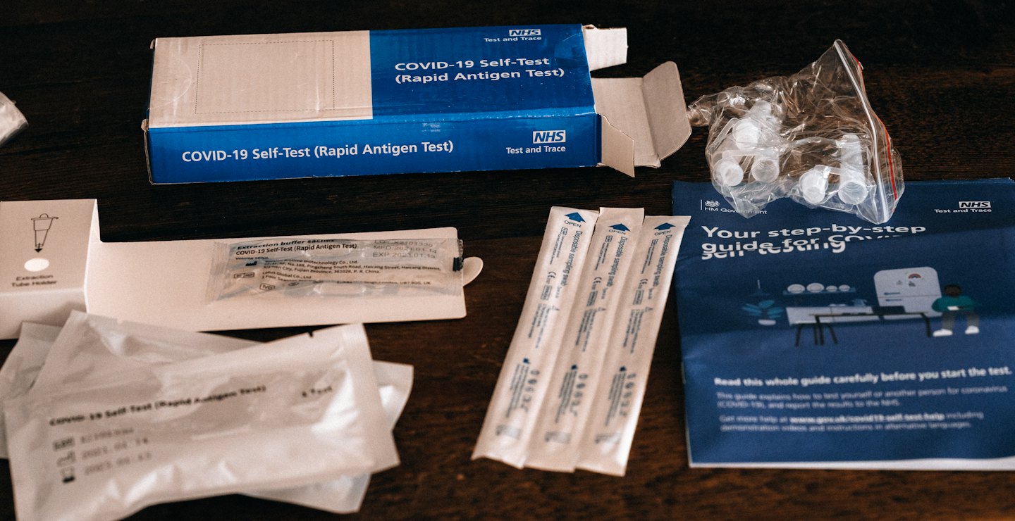 COVID-19 rapid test kit components arranged on a wooden table.